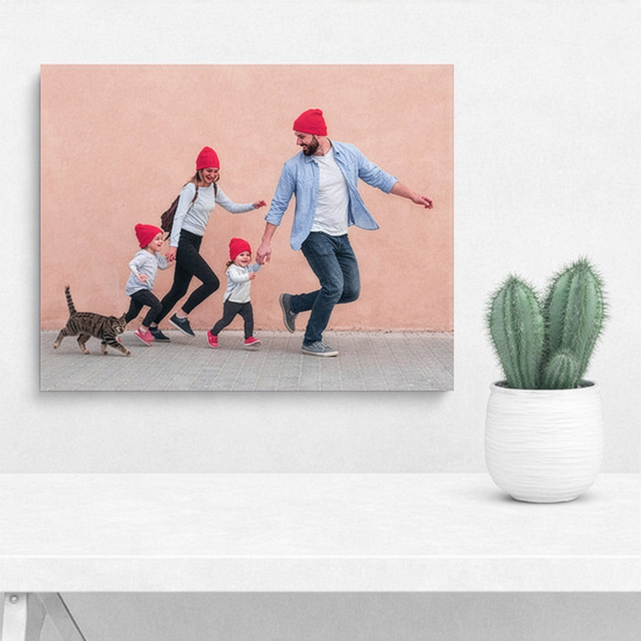 Quadro con famiglia che cammina con cane, cappelli rossi, cornice chiara.